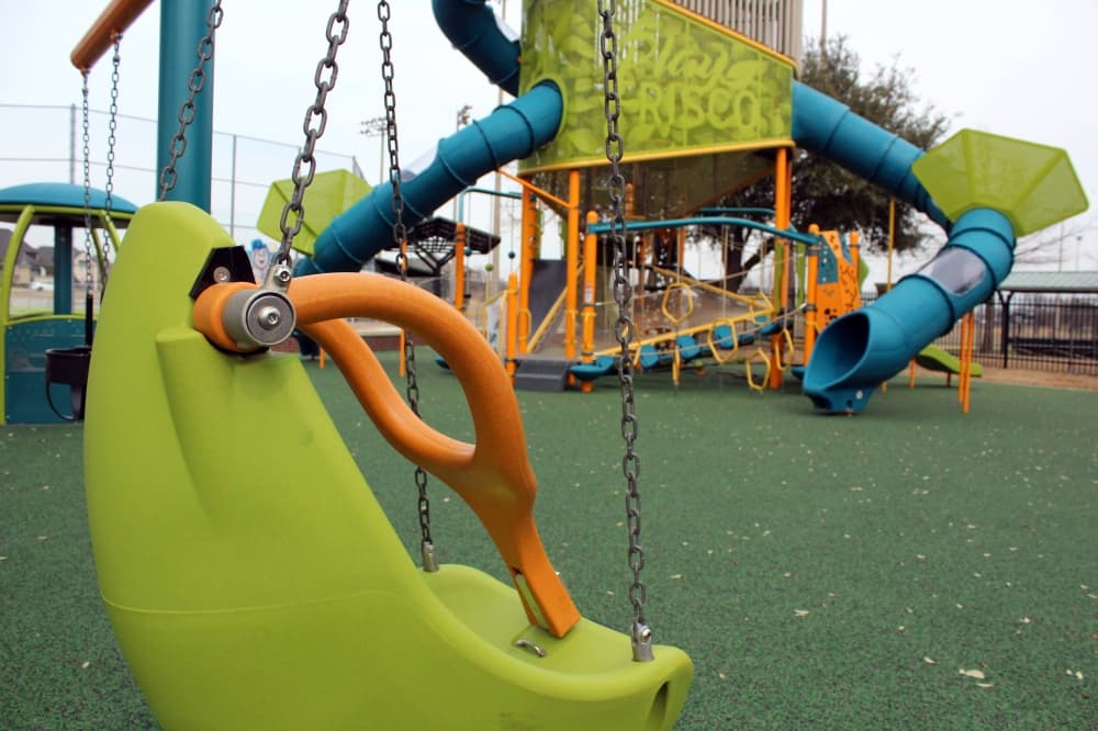 Adaptive playground featuring special needs swing in the foreground. 