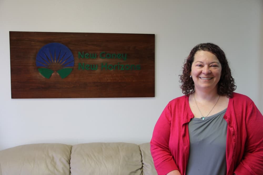 New Caney New Horizons Executive Director Darbie Lindsey stands in front of the nonprofit's logo inside the resale shop. (Wesley Gardner/Community Impact) 