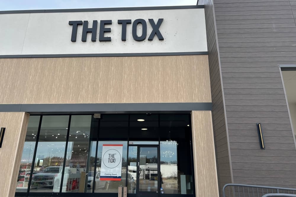 Exterior of a strip center featuring The Tox signage over one space. 
