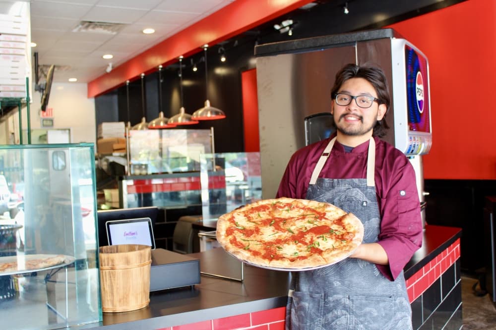 Owner holding pizza