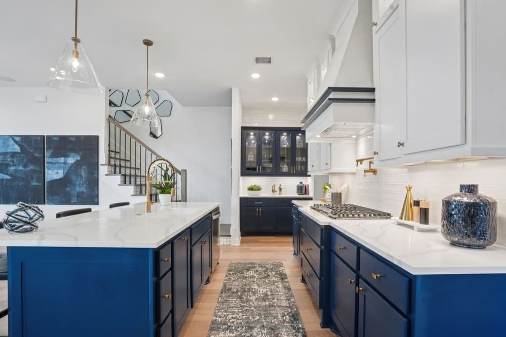 Open-concept kitchen and living room inside Drees Custom Homes at Austin Point featuring oversized island, double ovens, high ceilings and natural light in new construction home