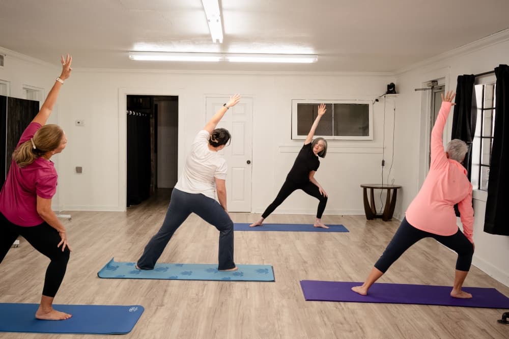 Debra Butts guides students through a lateral stretch during a class at her studio, offering hands-on instruction tailored to each participant.