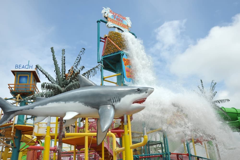 A shark statue in front of an aqua play structure with water pouring out