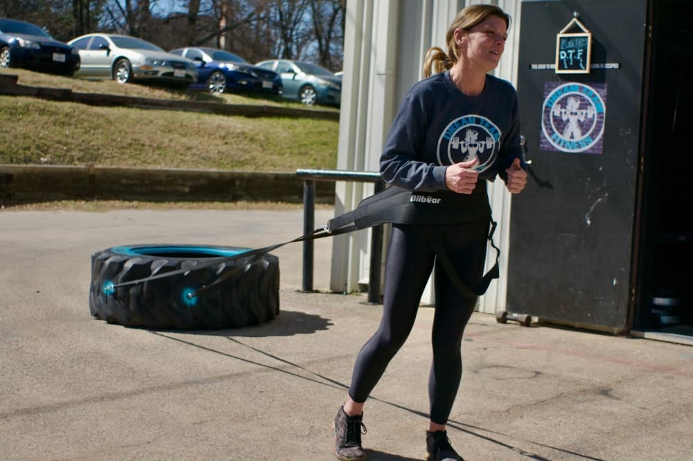 Evans demonstrates pulling the gym's 150-pound tire, which is one of the workout activities offered at Dream Team Fitness. (Adam Doe/Community Impact)
