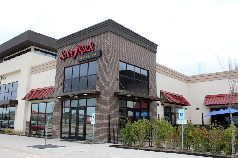 Exterior of a strip center featuring Spice Rack Indian Restaurant signage. 