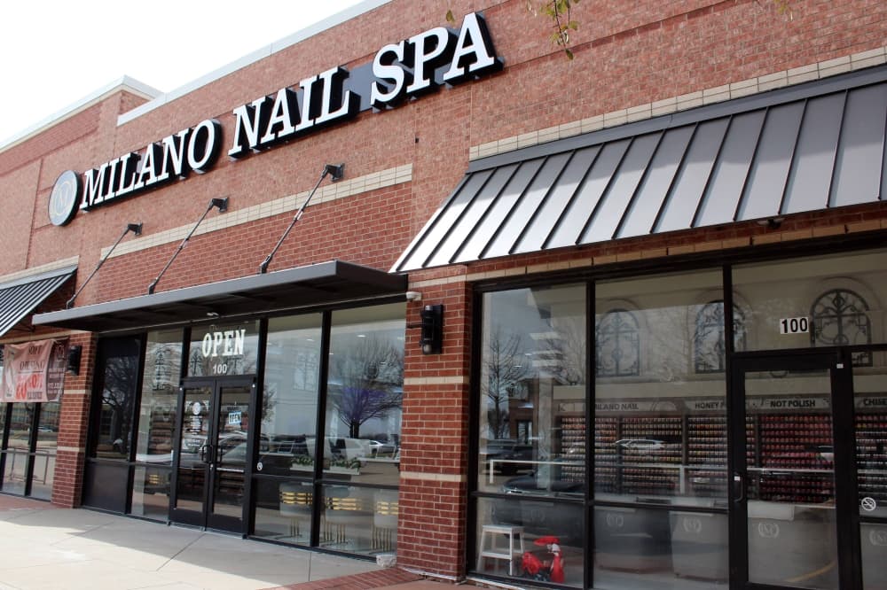 Exterior of a strip center featuring Milano Nail Spa signage. 