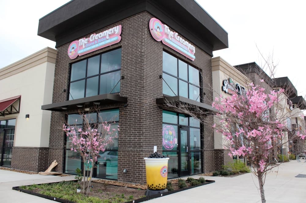 Exterior of a corner lot in a strip center featuring The Creamery Stone & Boba signage. 