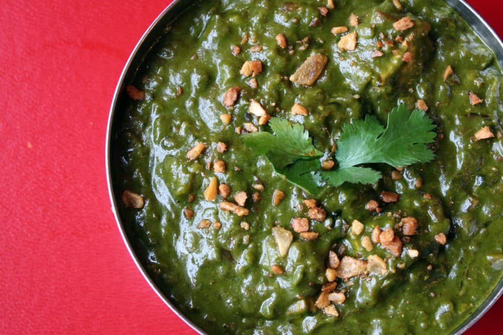 Overview of green dish in a bowl sitting on a red background. 