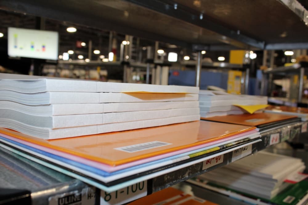 Pages stacked on top of book covers in a manufacturing facility. 