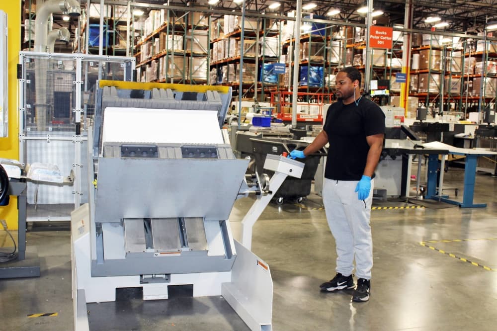 Male looking at a computer screen next to a machine in a manufacturing facility. 