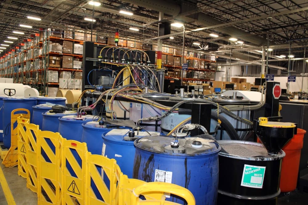 Vats of ink with tubes attached in a manufacturing facility. 