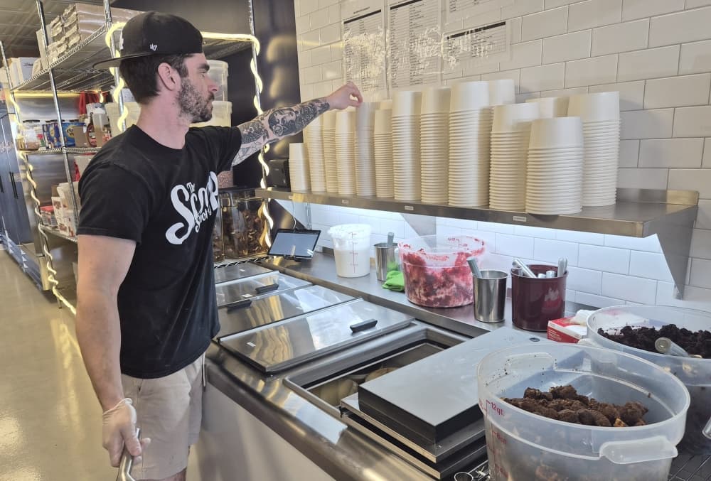 The Scoop N Scootery founder Austin Crittenden prepares an ice cream sundae during the Fort Worth location's soft opening. (Patricia Ortiz/Community Impact)
