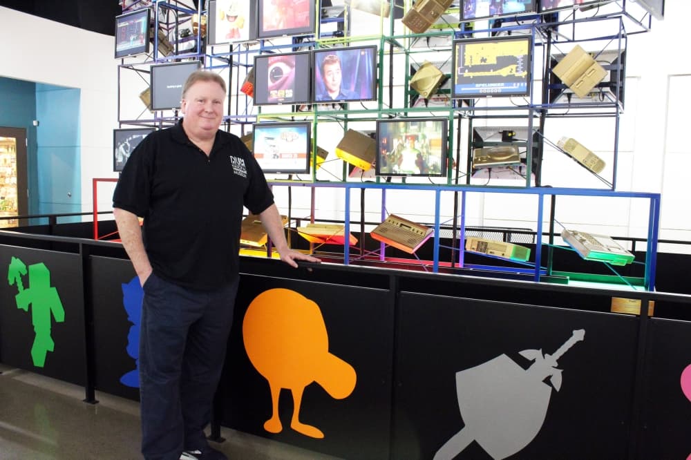 Male standing in front of a videogame themed museum display. 