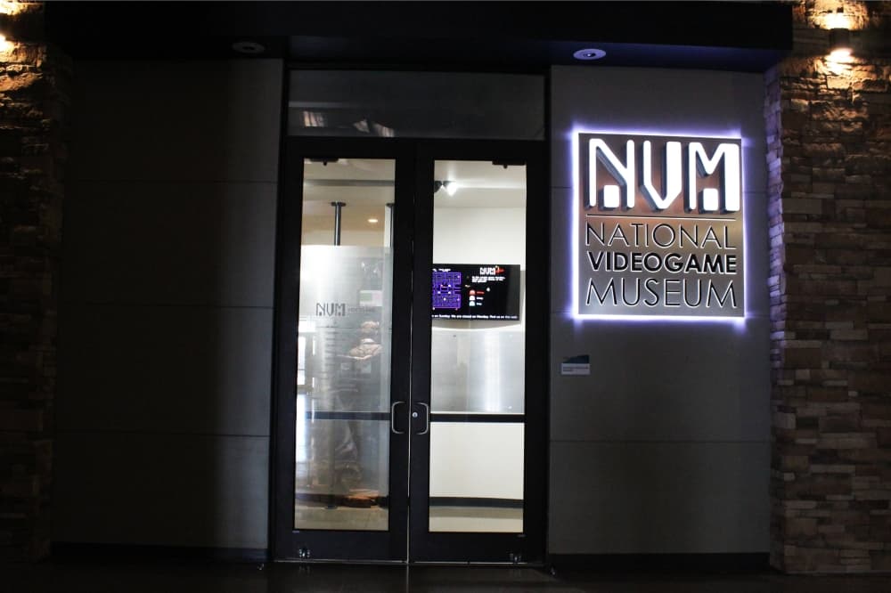 Exterior of a dimly lit hall featuring lighted National Videogame Museum signage. 