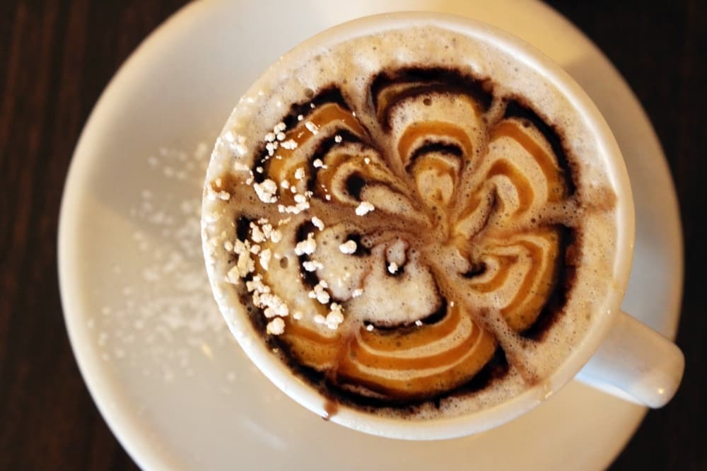 Overview of a cappuccino in white cup on a white saucer.