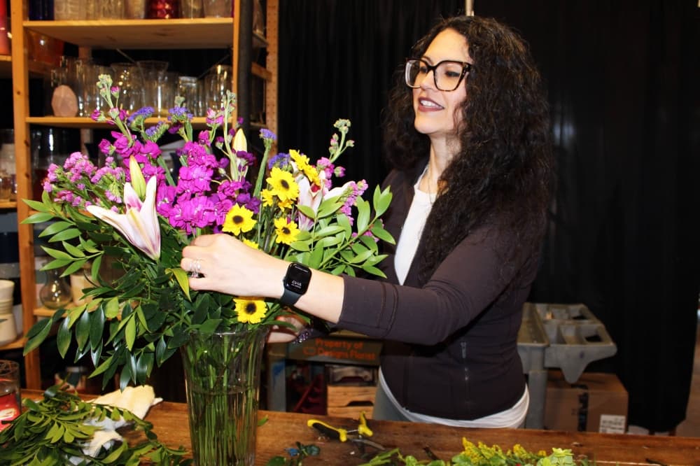 Female adding flowers to a flower arrangement in a flower shop. 