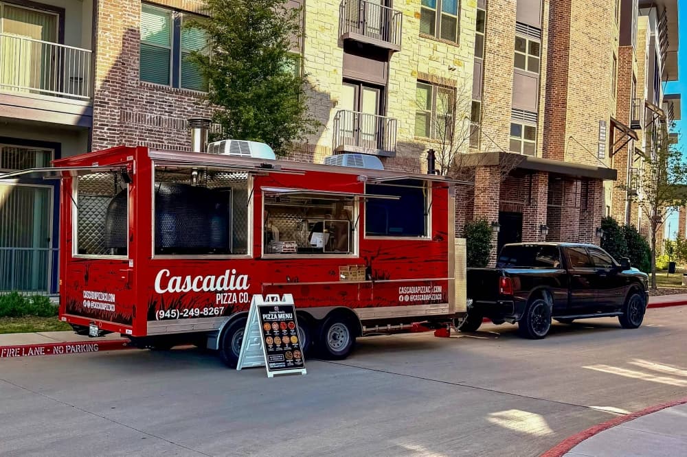 Food truck featuring Cascadia Pizza Co. branding parked in front of an apartment building. 