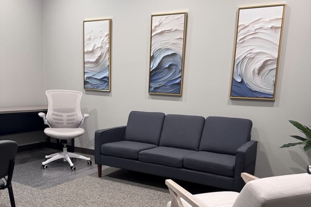 the interior of a mental health clinic with blue and white paintings on the wall and a couch and other furniture