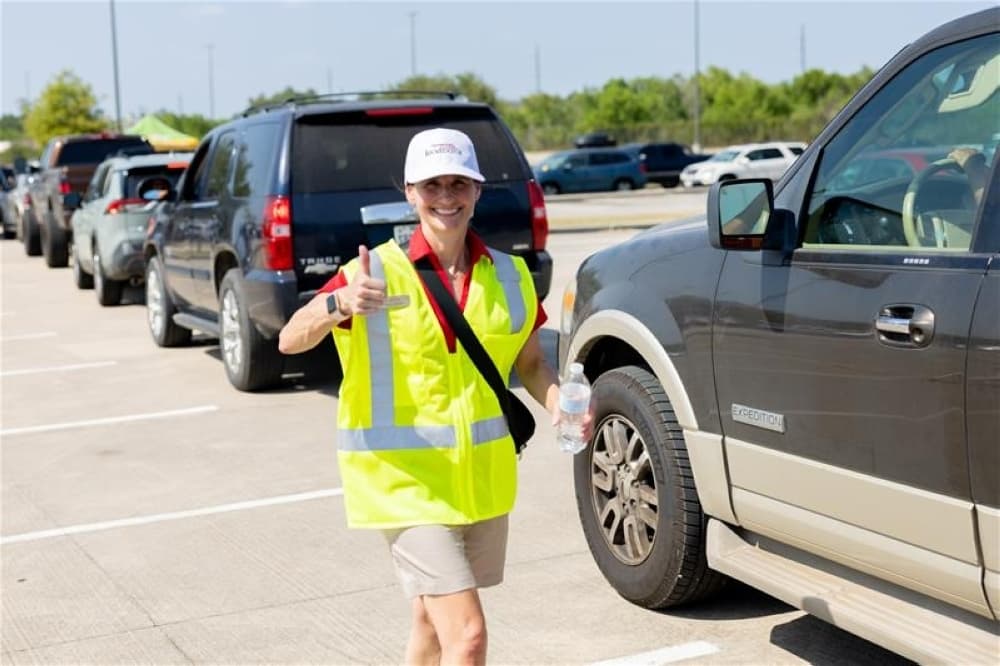 woman in yellow vest with car line