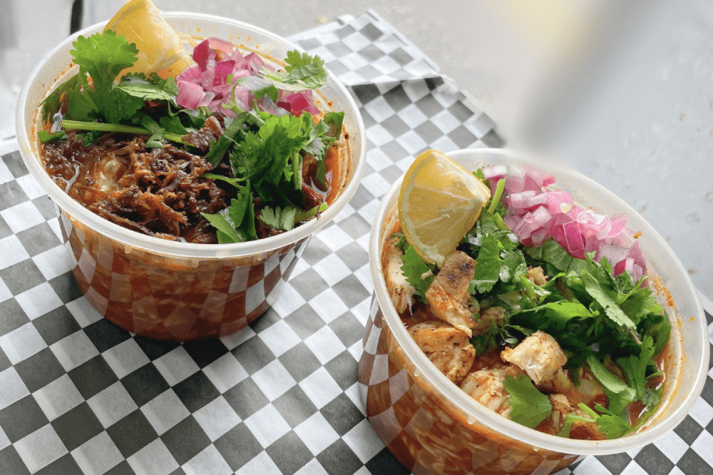 Two ramen bowls topped with cilantro, onions and cheese.