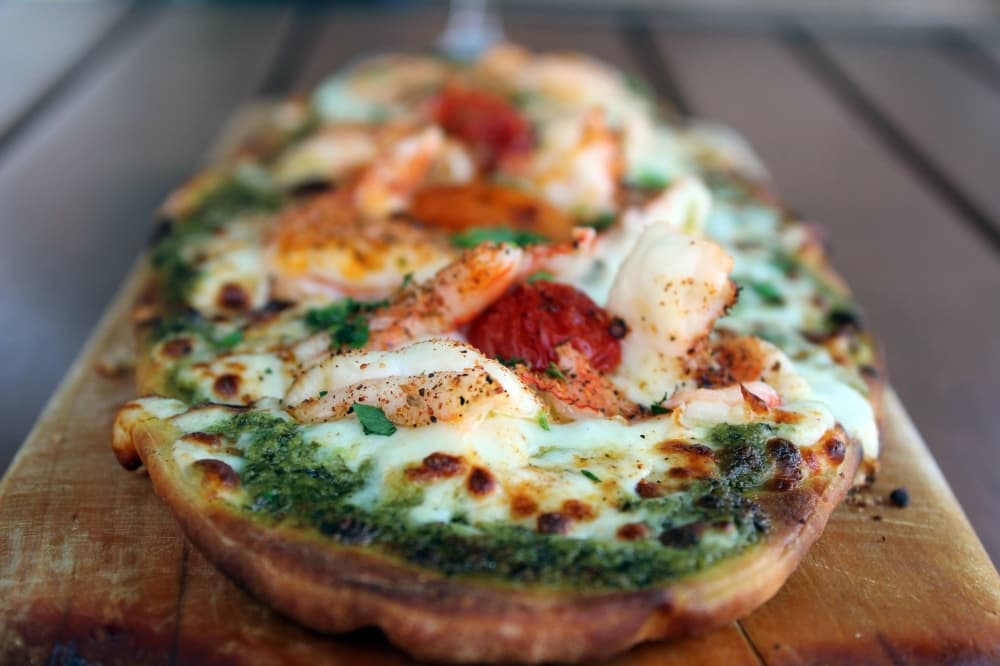 Side view of a flatbread pizza on a serving board. 