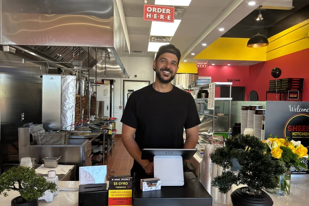 Male standing at a restaurant counter behind the point of sale device. 