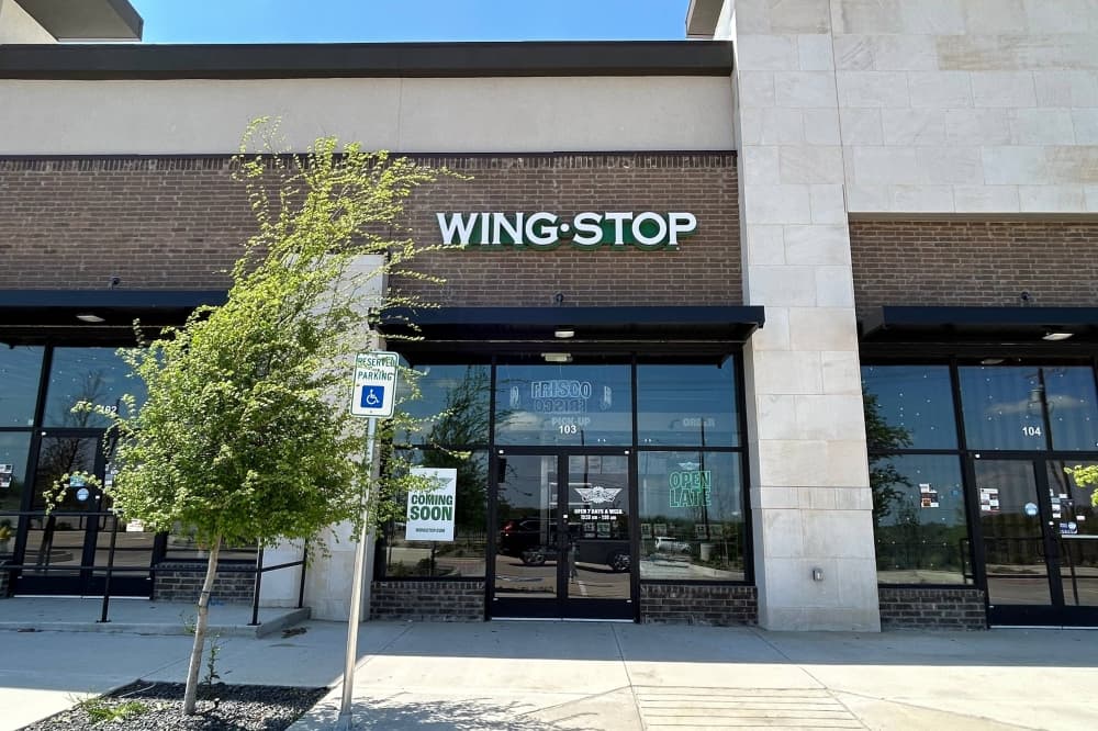 Exterior of a strip center featuring Wingstop signage over one space. 