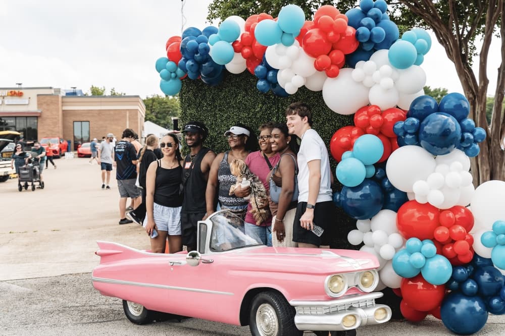 people standing near a pink car