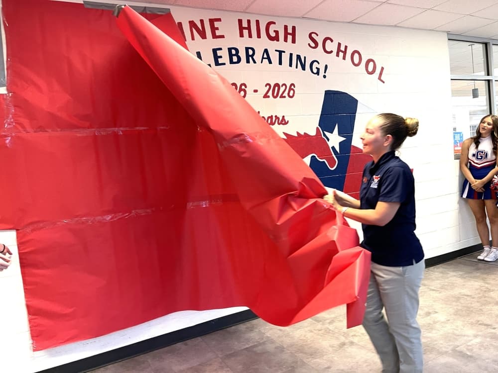Kristi Rucker, a GHS art teacher, unveils a mural at Grapevine High School April 23.
