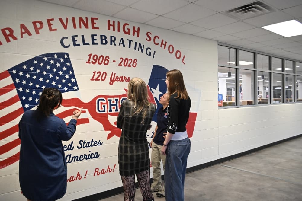 The artists who designed a new mural inside Grapevine High School inspect their work. (Connor Pittman/Community Impact)