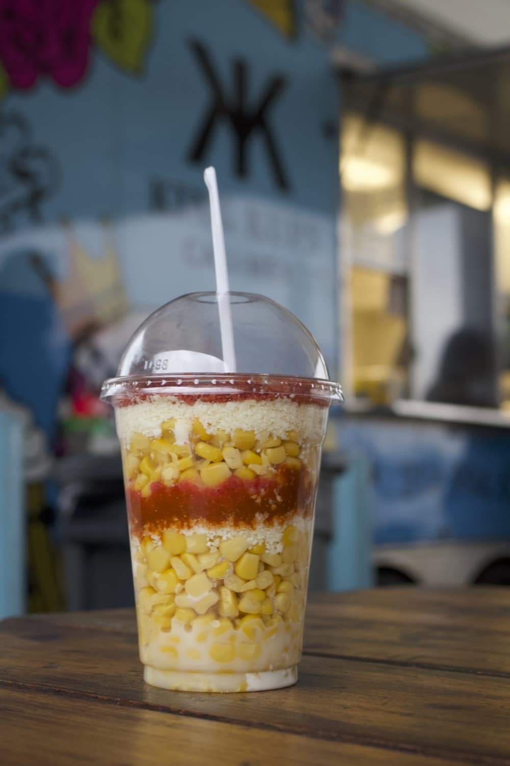a cup of corn with sauce and seasoning