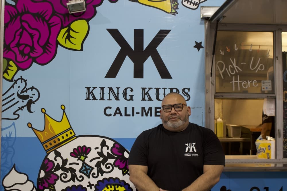 owner of a restaurant standing in front of a food truck
