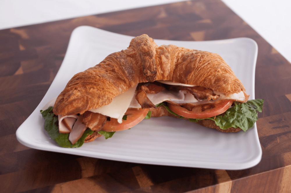 The Cordon Bleu sandwich on a flaky house-made croissant at Blue Baker, featuring artisan sandwiches and fresh bakery items in College Station TX