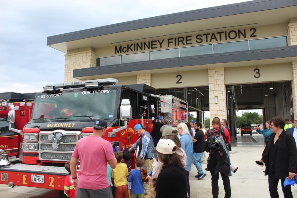 Grand opening attendees wipe a fire truck down with rags after it was sprayed with water. 