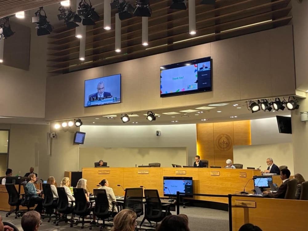 The Travis County Commissioners Court chamber during the May 5 meeting, with commissioners seated at the dais and a "Thank You" Raising Travis County slide displayed on the overhead screens.
