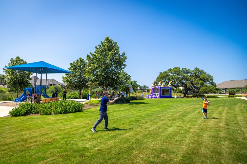 dad throwing baseball to his child in green field