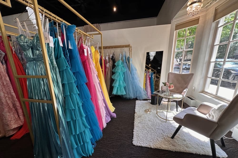 A rack of dresses and seats by a window