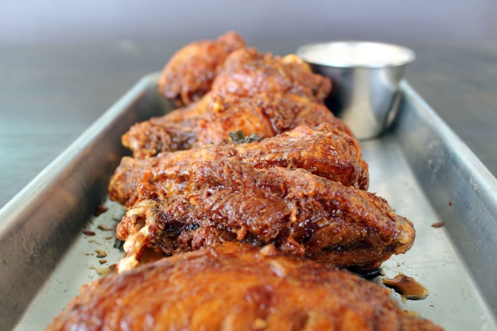 Cooked chicken wings on a silver rectangular serving plate. 