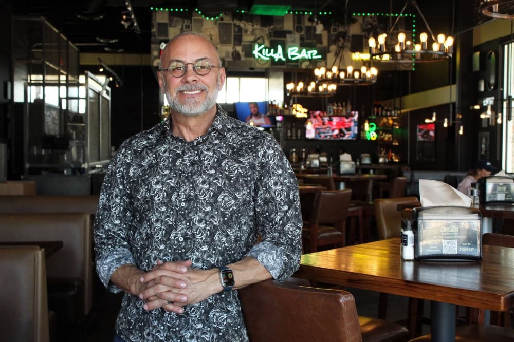 Male standing next to a bar-height table in a restaurant. 