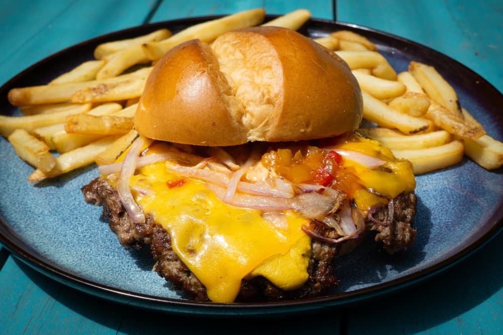 The Purely Burger includes a smashed beef patty, grilled onions, mustard, peach aioli, bourbon bacon jam and cheddar on a brioche bun. (Courtesy Purely Provisions)