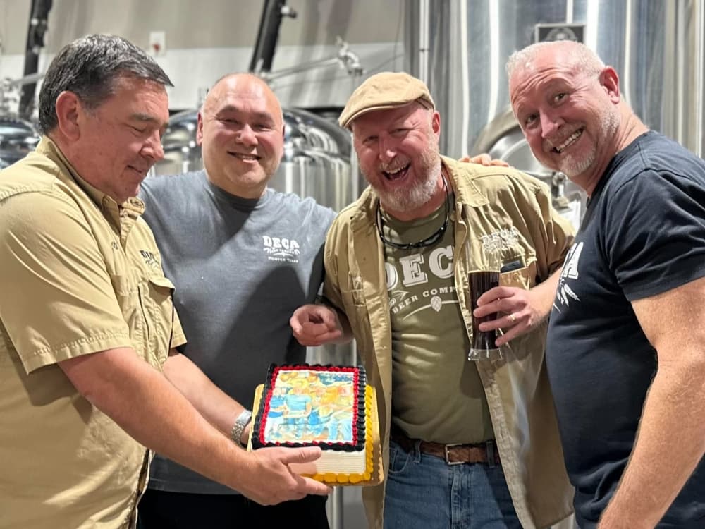 Jason Doornik, Cody Evans, Heath Cleaver and Jeff Angell smiling with a cake