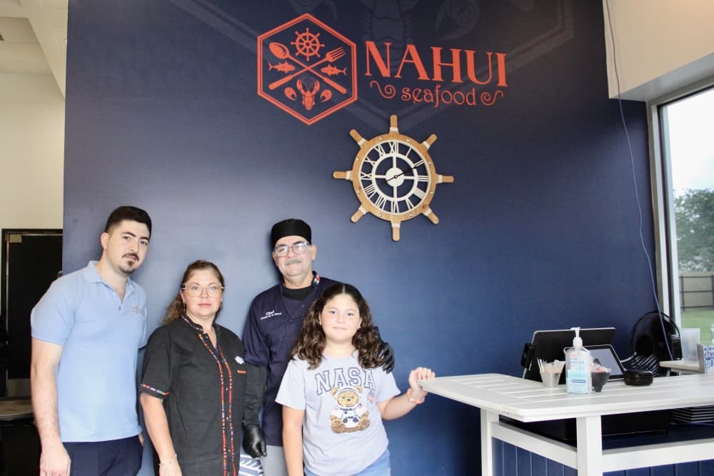 family with Nahui Seafood sign