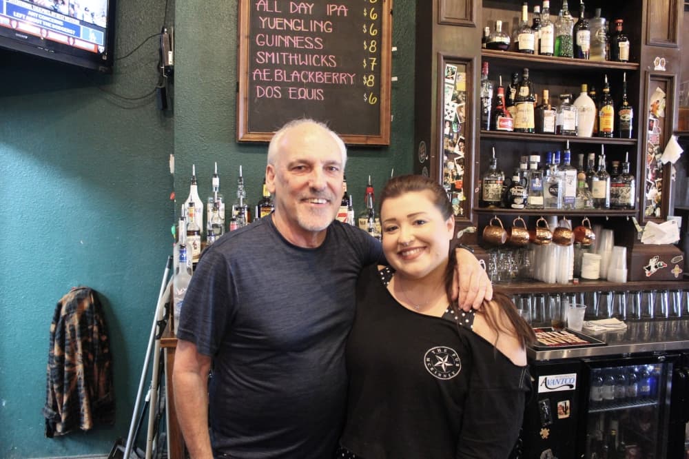 A man and a woman stand behind a bar