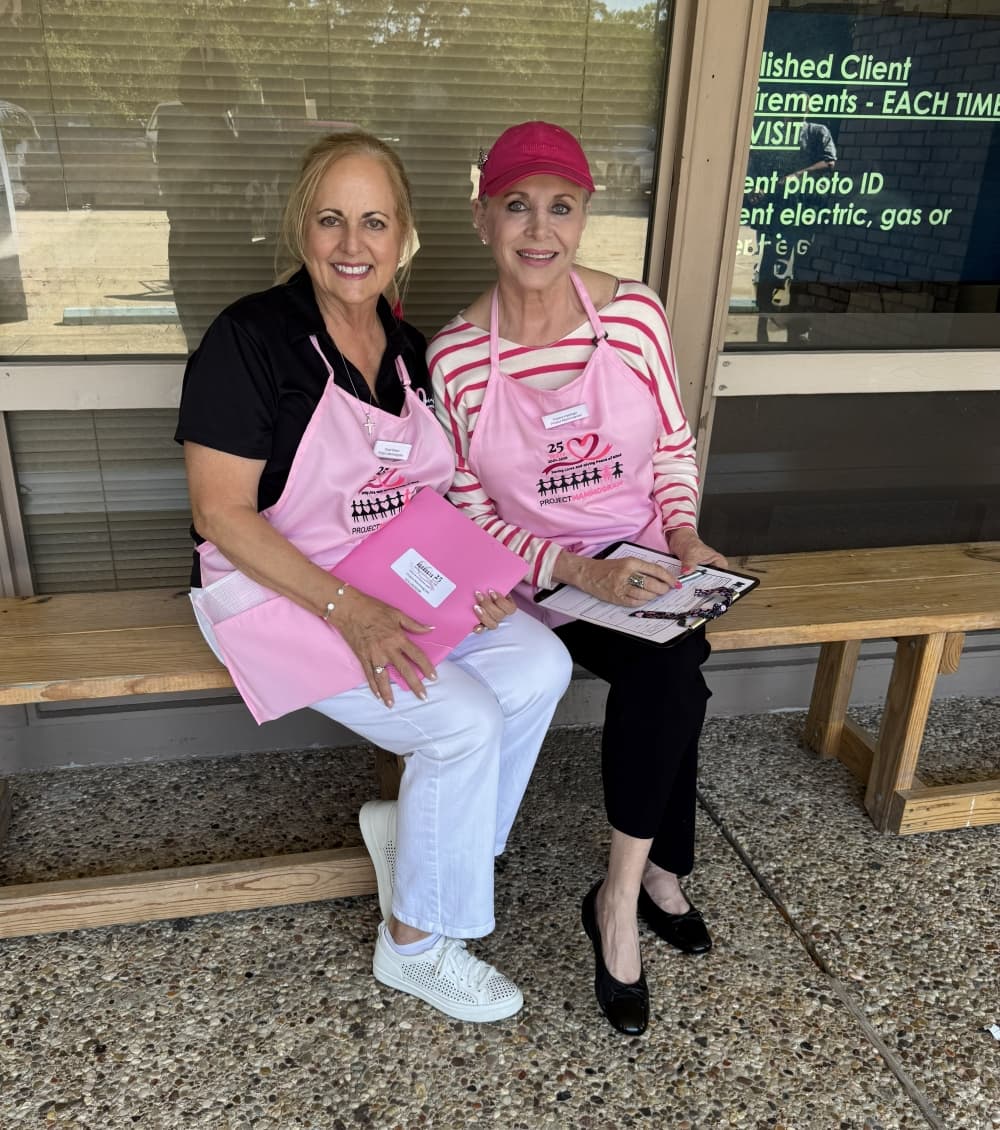 Kingwood Women's Club members Carol Prince and Ronna Hardage sit on a bench wearing pink
