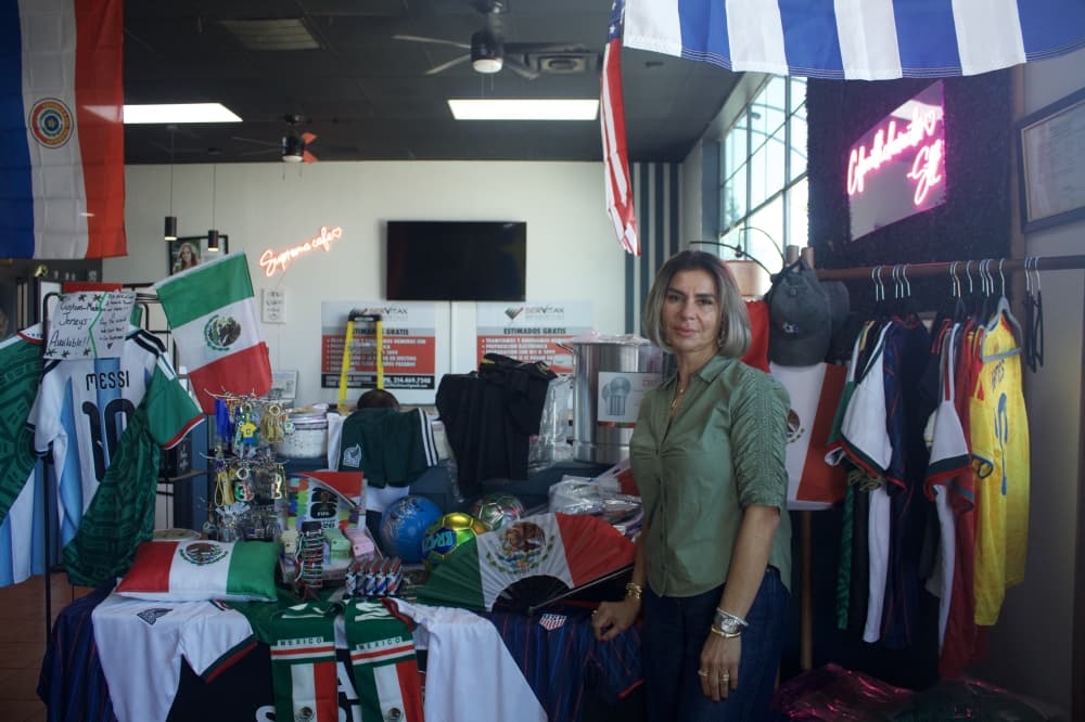 La Suprema owner Summer Bannat standing in front of a table with World Cup merchanidse like flags and jerseys