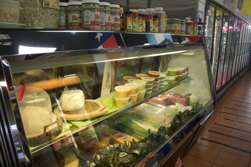 A deli counter case with meats and cheeses