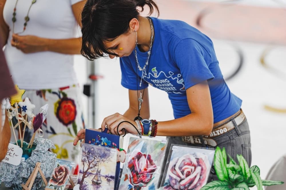 Young artist fixing mini canvases for sale on her table