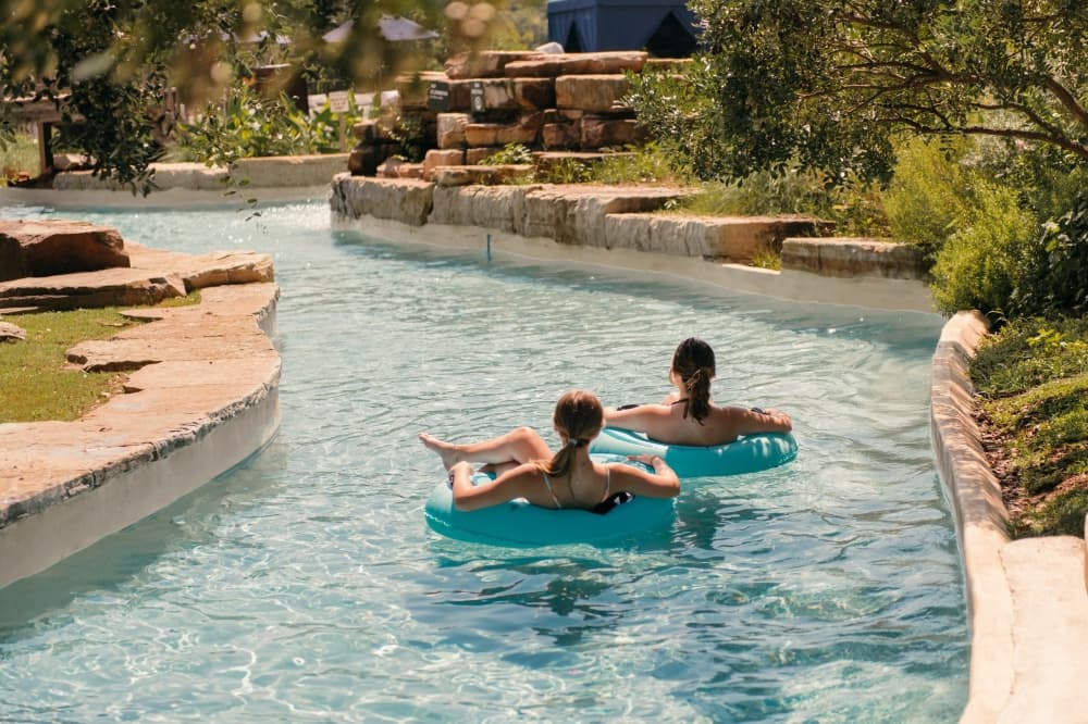 Two guests float in inner tubes along a resort waterway at Hyatt Regency Lost Pines Resort & Spa.