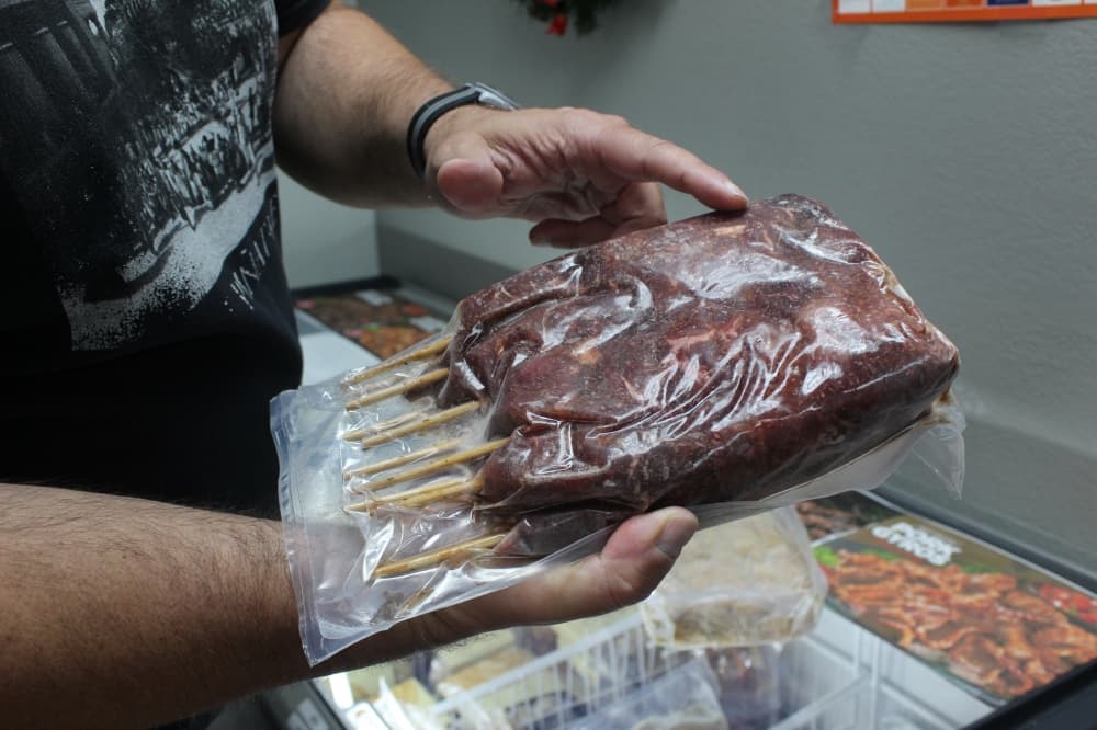 A man in a black shirt holding a package of kebab meat