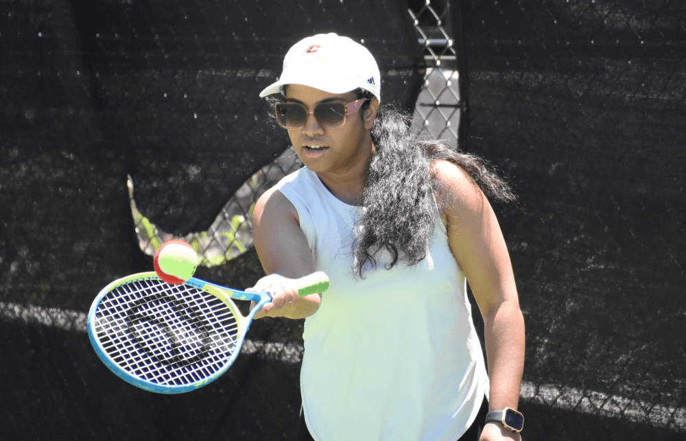 woman hitting tennis ball with racket